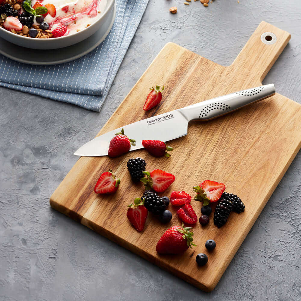 Cuisine::pro® iD3® Chefs Knife 6" on wooden cutting board with mixed berries and a bowl of fruit salad