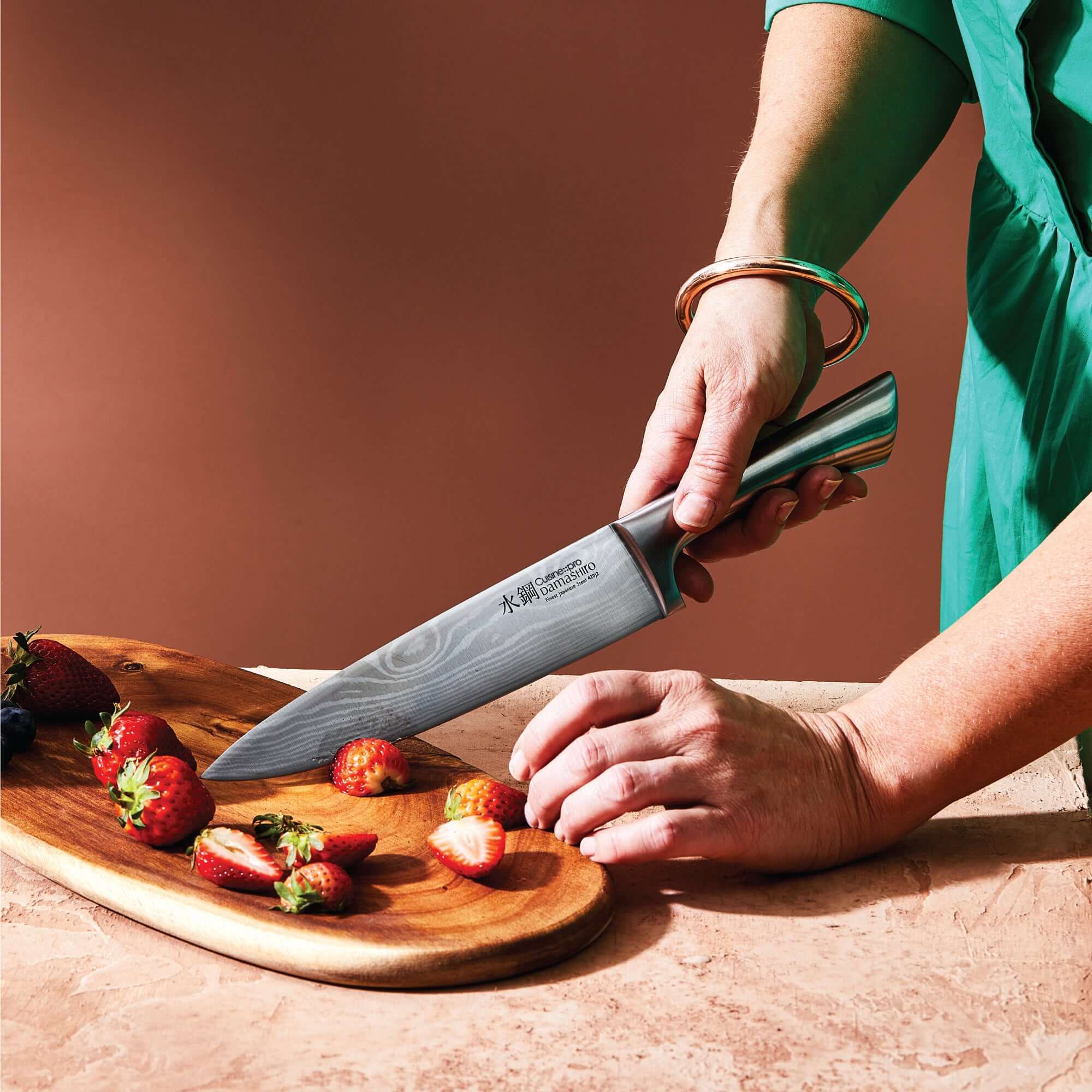 Chef slicing strawberries with Cuisine::pro® Damashiro® Meiyo knife from the 7 piece knife block set, showcasing precision and superior quality.