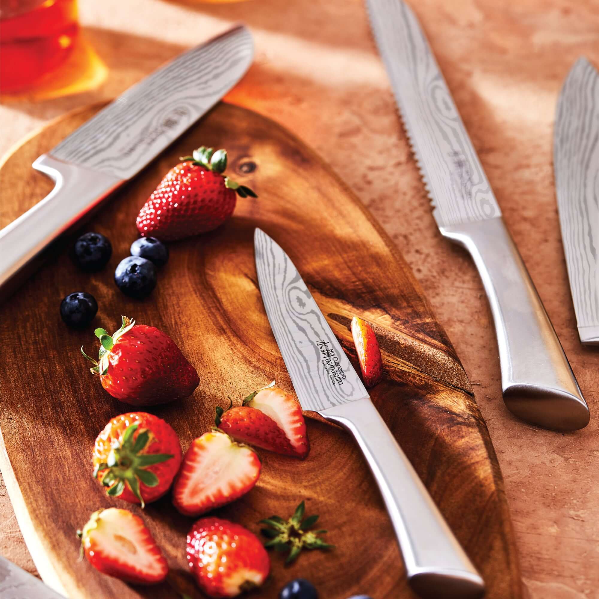 Japanese steel kitchen knives on wooden board with strawberries and blueberries