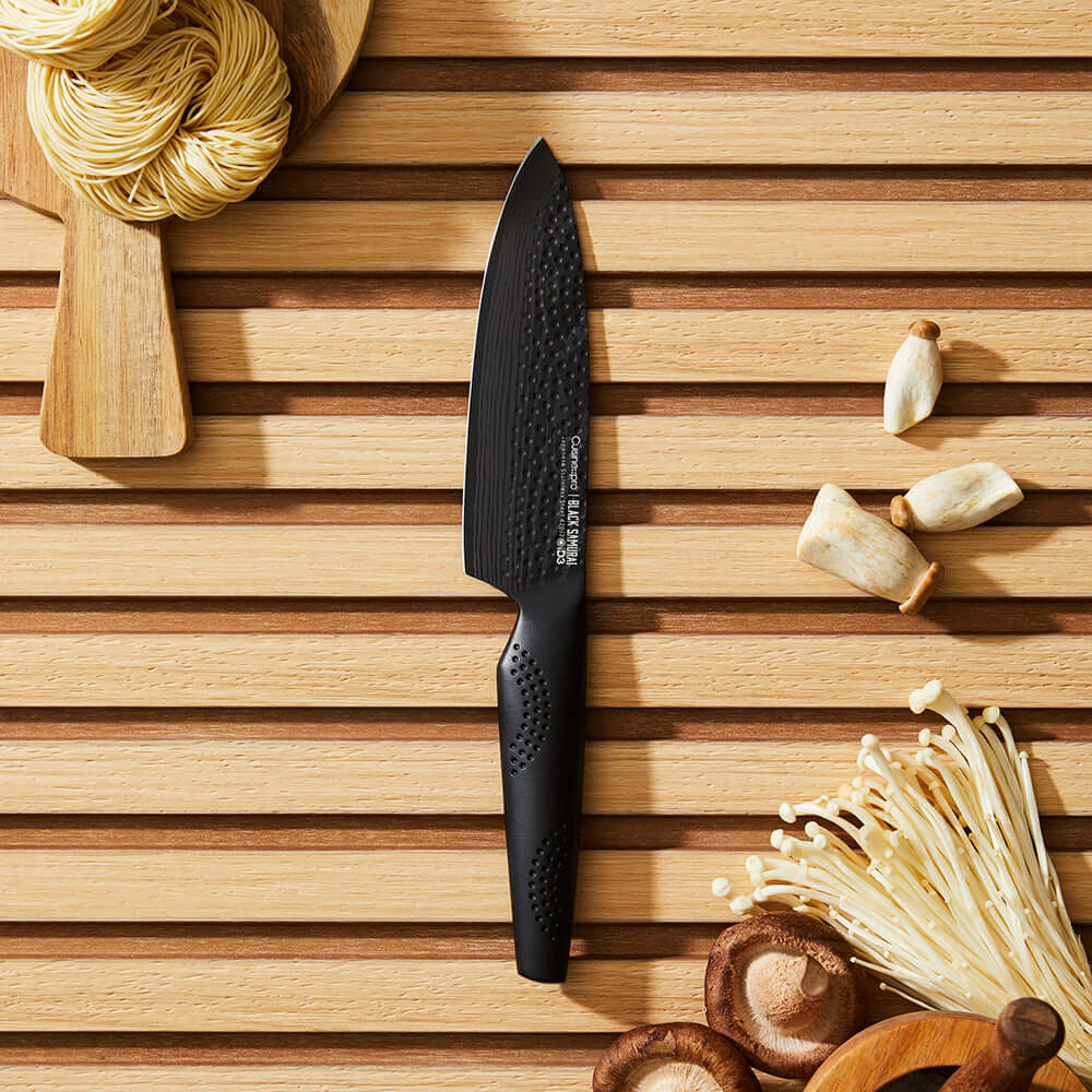 Cuisine::pro® iD3® BLACK SAMURAI™ Chefs Knife 6" on wooden cutting board with mushrooms and noodles