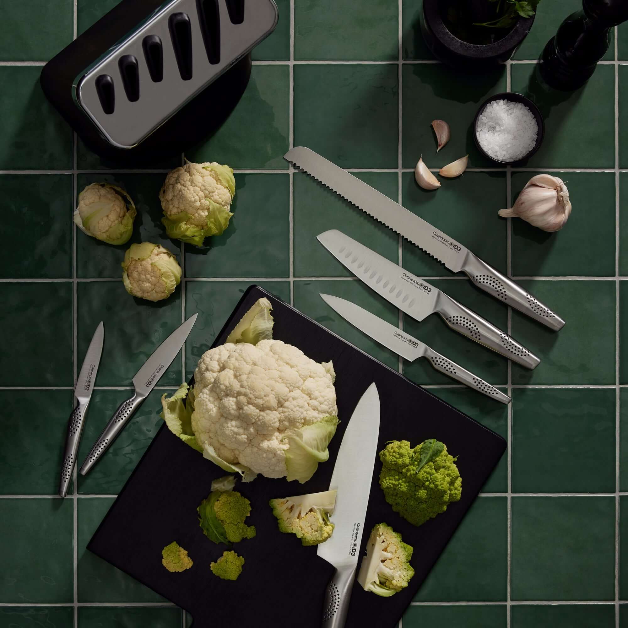 Cuisine::pro® iD3® Kobe 7 Piece Knife Block with Japanese steel knives on green tile background and fresh cauliflower on cutting board